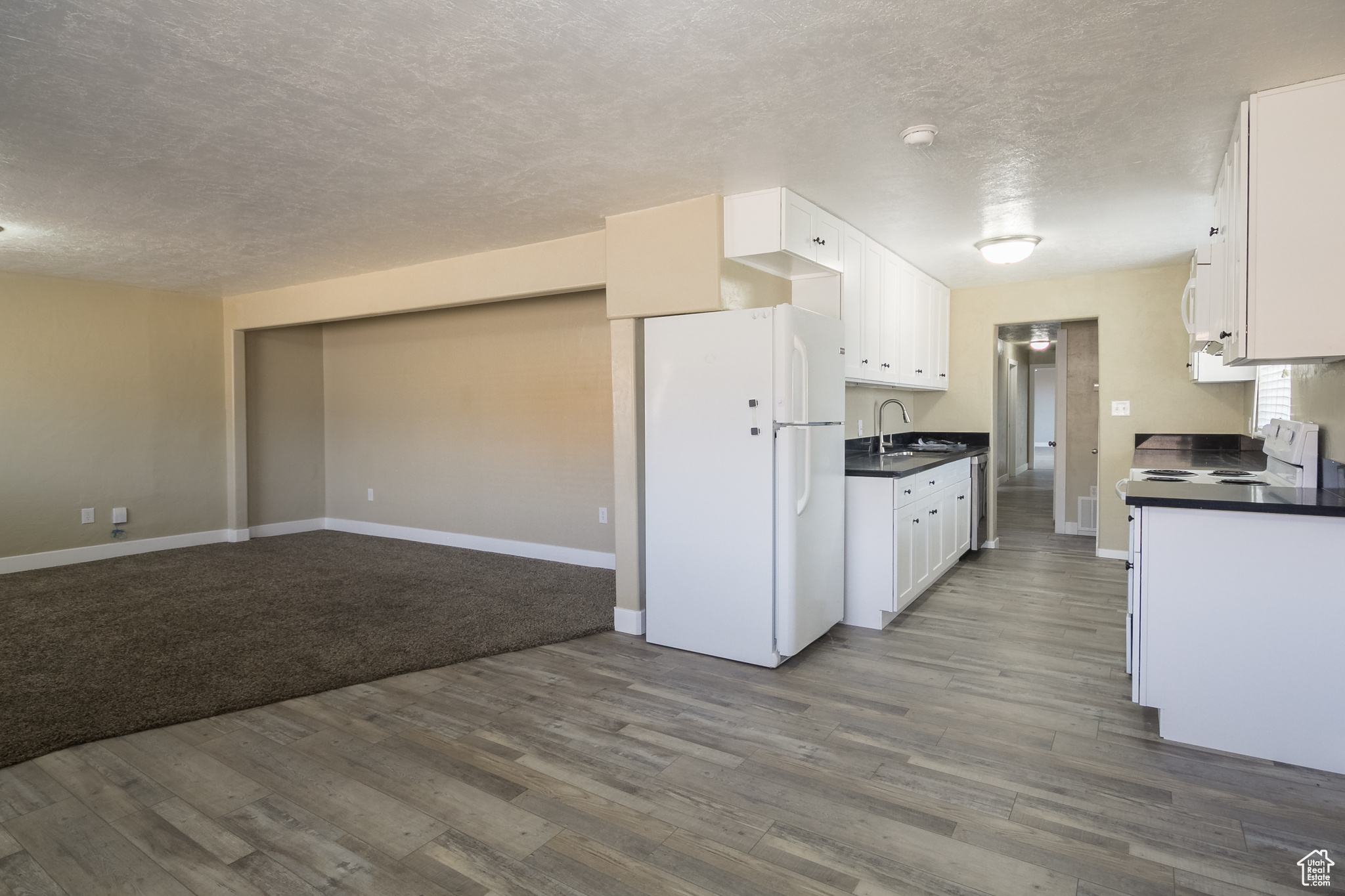 Kitchen featuring white cabinets, dark hardwood / wood-style floors, white appliances, and sink