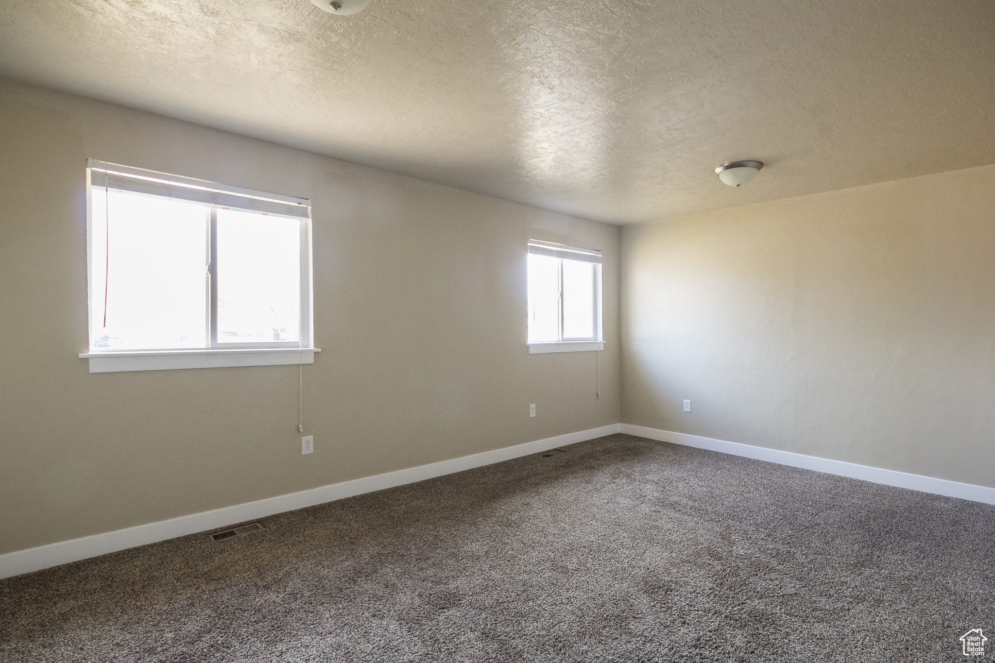 Carpeted empty room featuring a textured ceiling