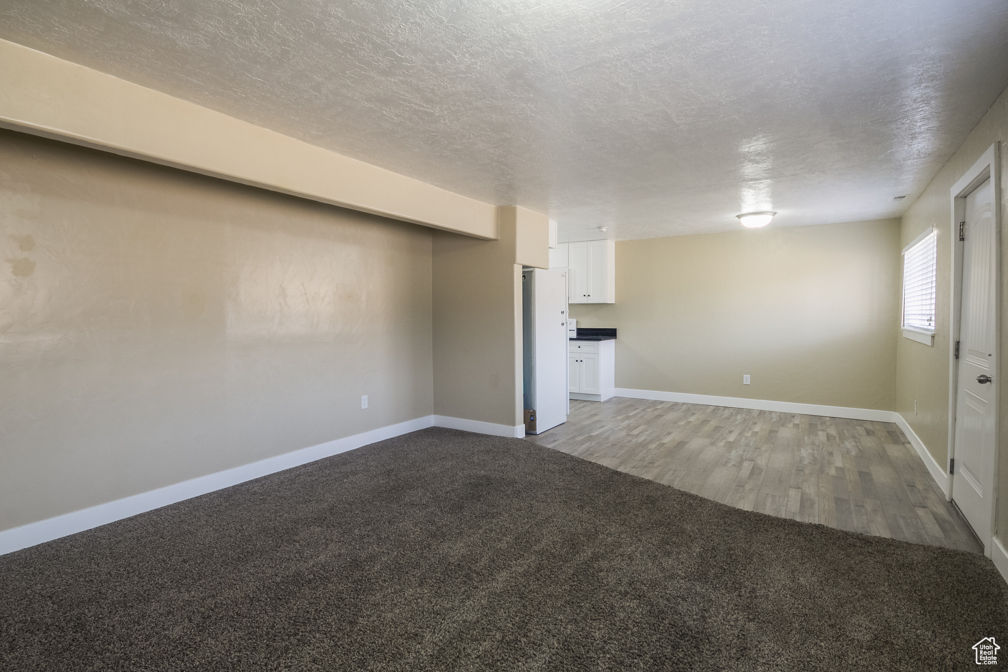 Unfurnished living room featuring carpet flooring and a textured ceiling