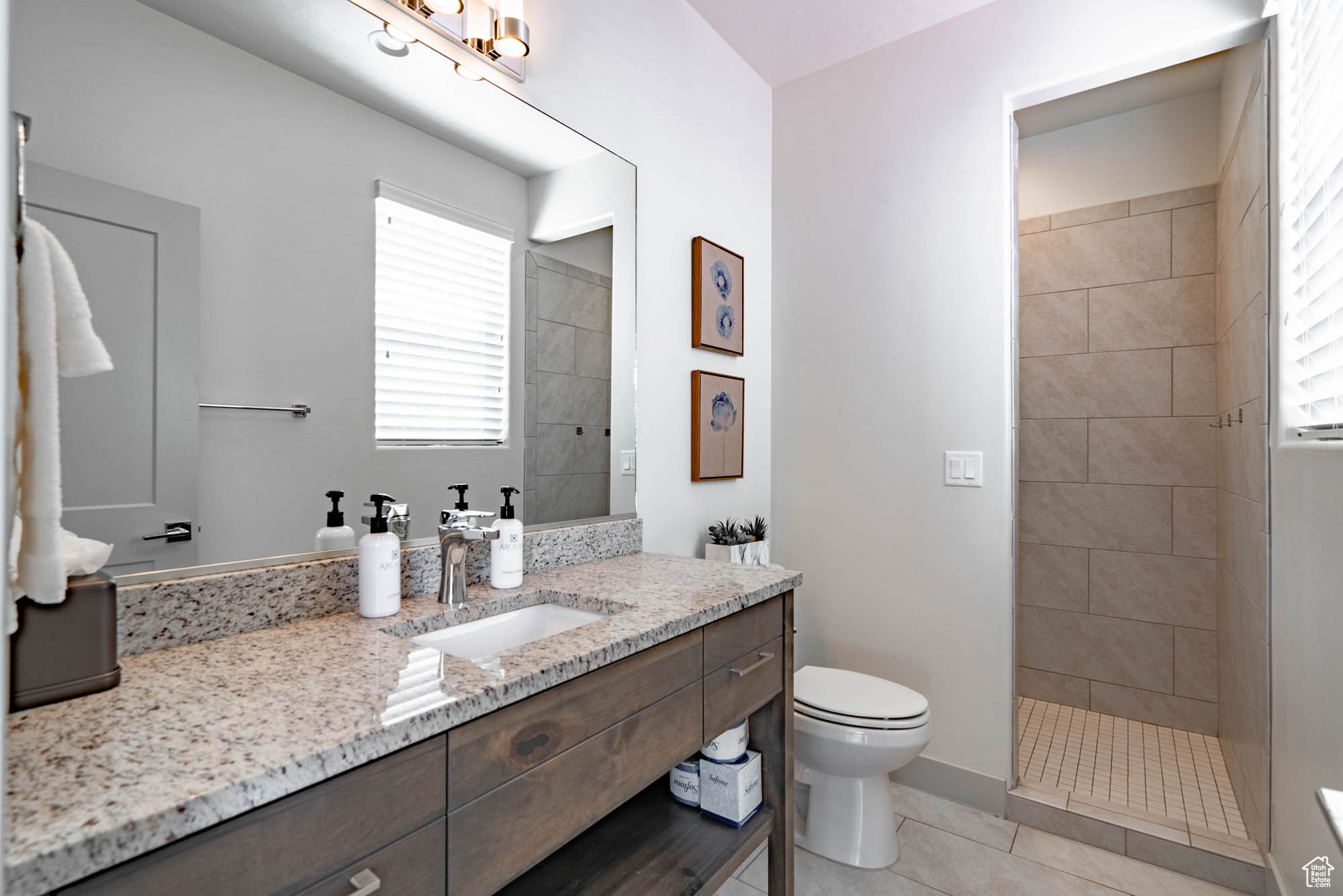 Bathroom with tile patterned floors, vanity, a tile shower, and toilet