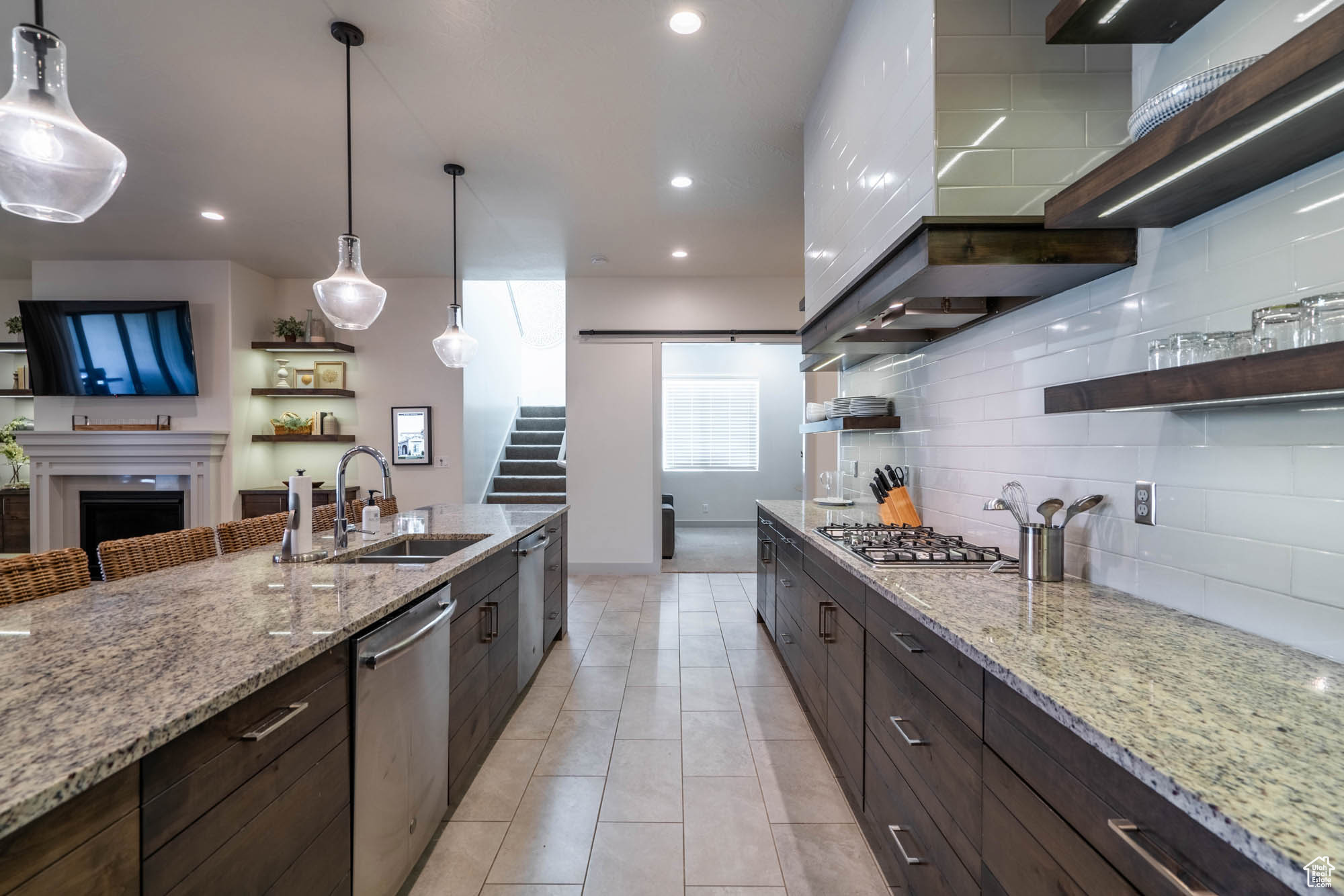 Kitchen with light stone countertops, sink, pendant lighting, and appliances with stainless steel finishes