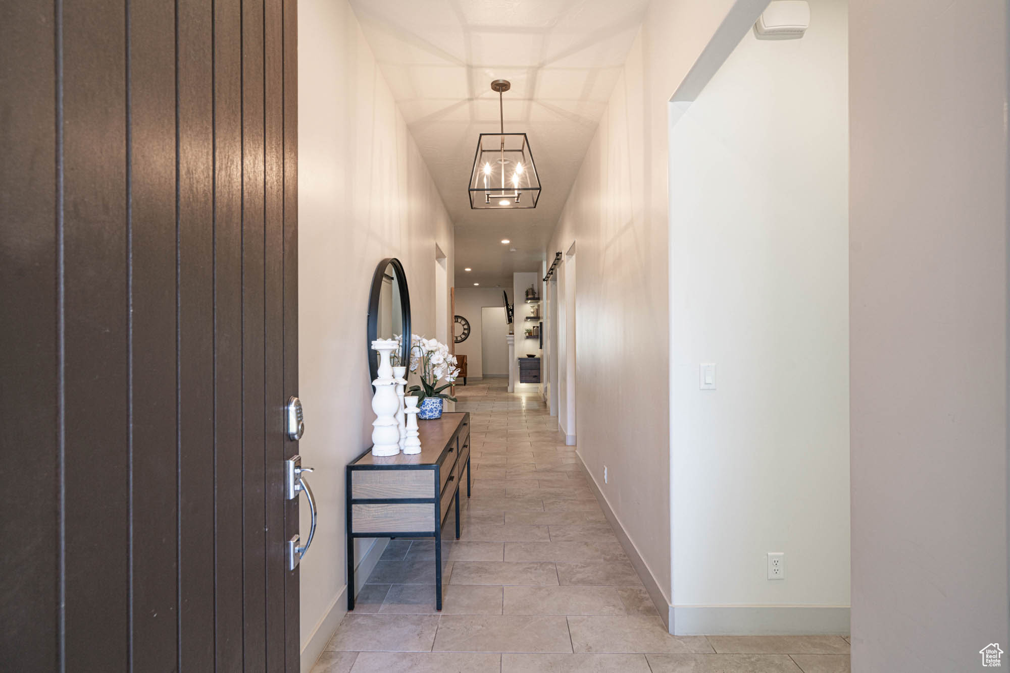 Corridor featuring light tile patterned flooring and an inviting chandelier