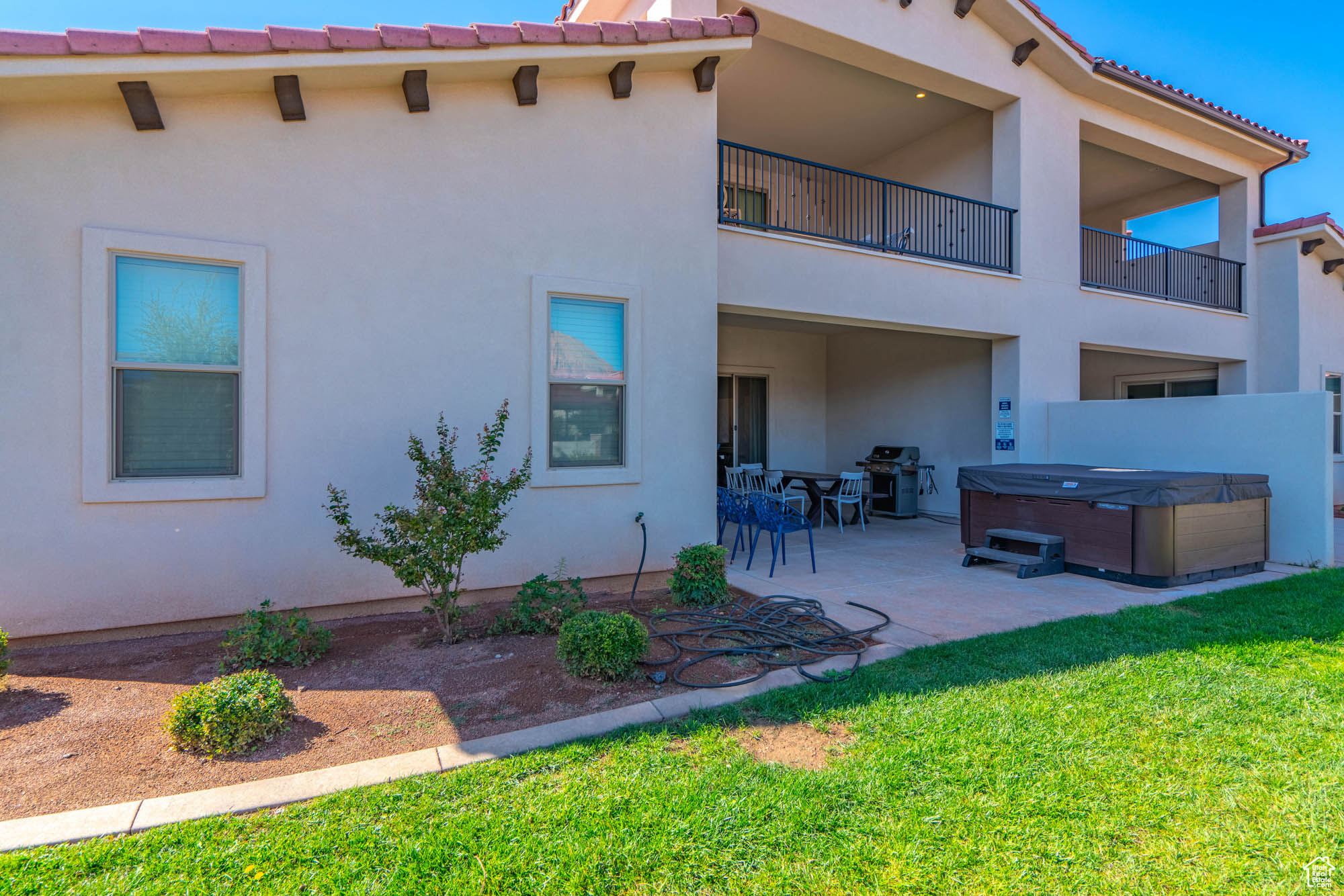 Back of property featuring a patio area, a yard, and a hot tub