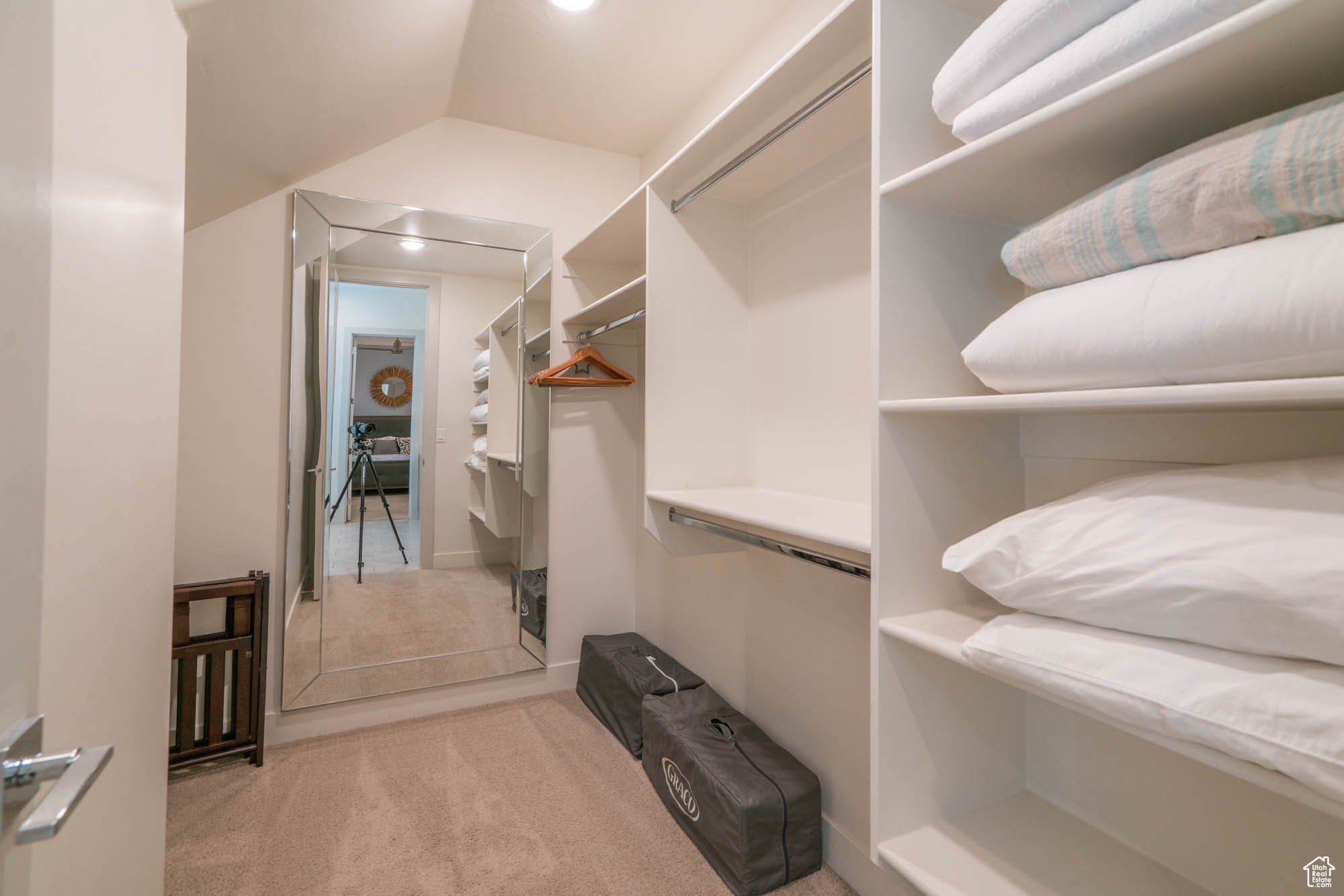 Walk in closet with light colored carpet and vaulted ceiling