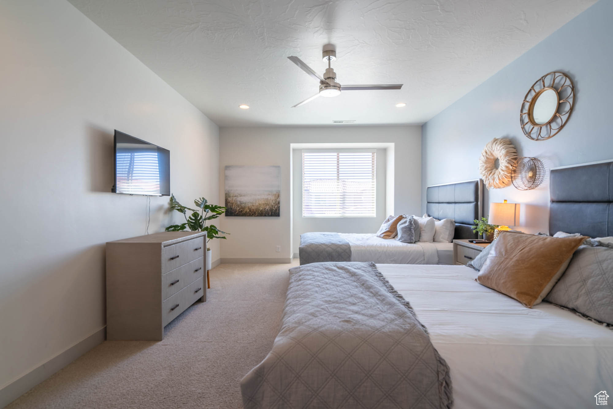 Bedroom with ceiling fan, light colored carpet, and a textured ceiling