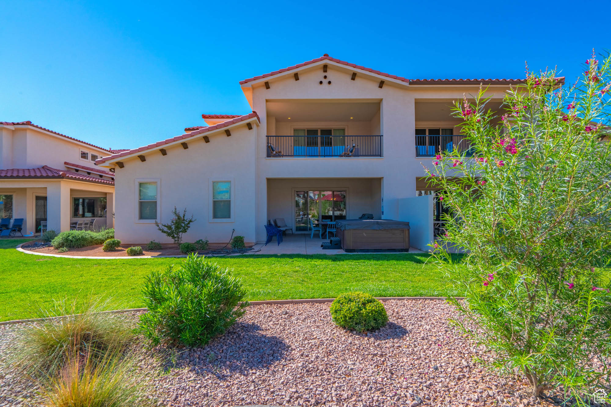 Rear view of house featuring a lawn, a patio area, and a hot tub