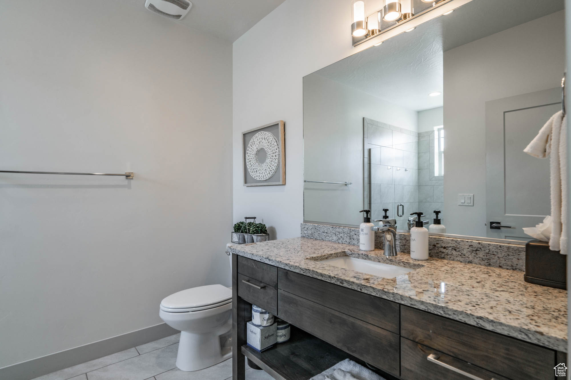 Bathroom featuring toilet, vanity, tile patterned floors, and a shower with shower door