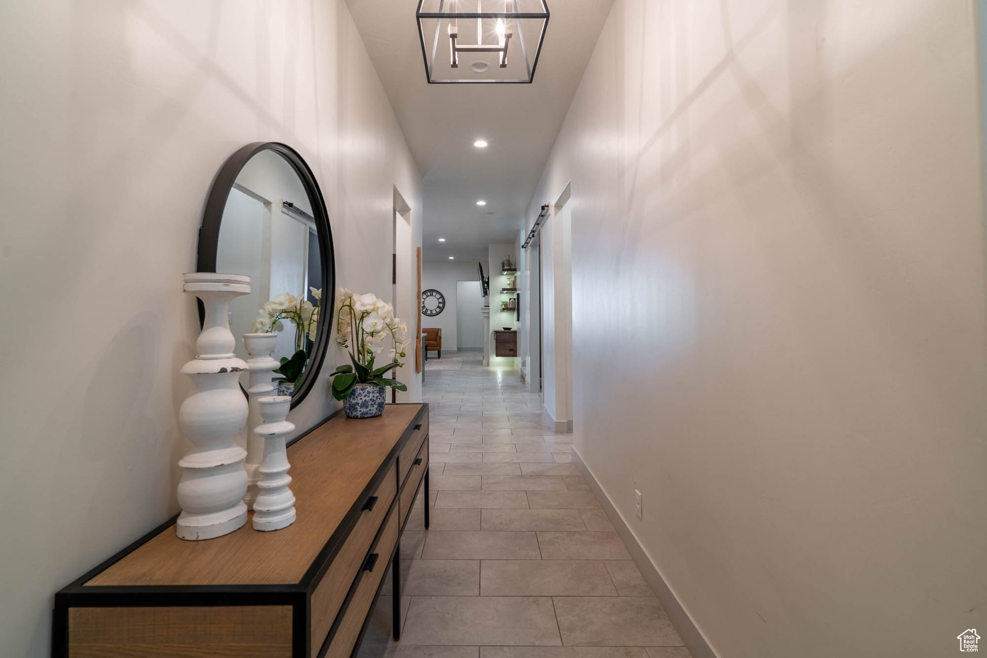 Hallway with a barn door and a notable chandelier