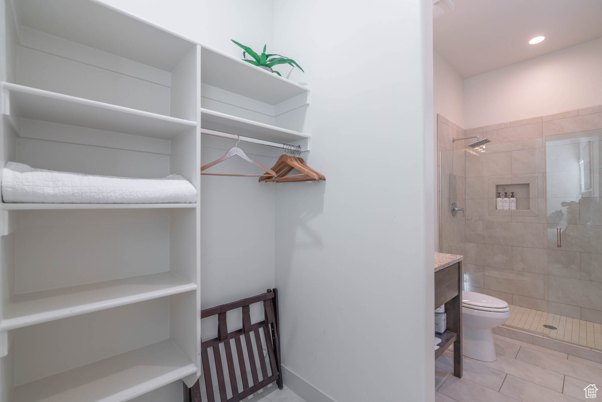 Interior space with tiled shower, tile patterned floors, vanity, and toilet