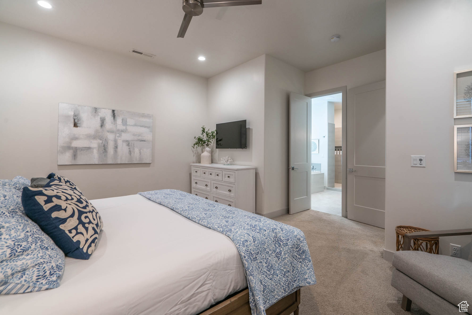 Bedroom with ceiling fan, light colored carpet, and ensuite bathroom