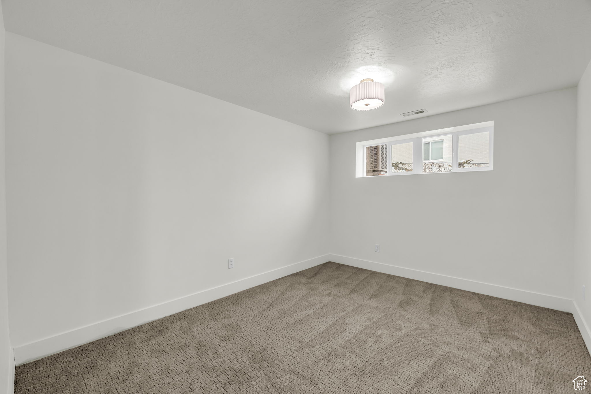 Carpeted spare room with a textured ceiling