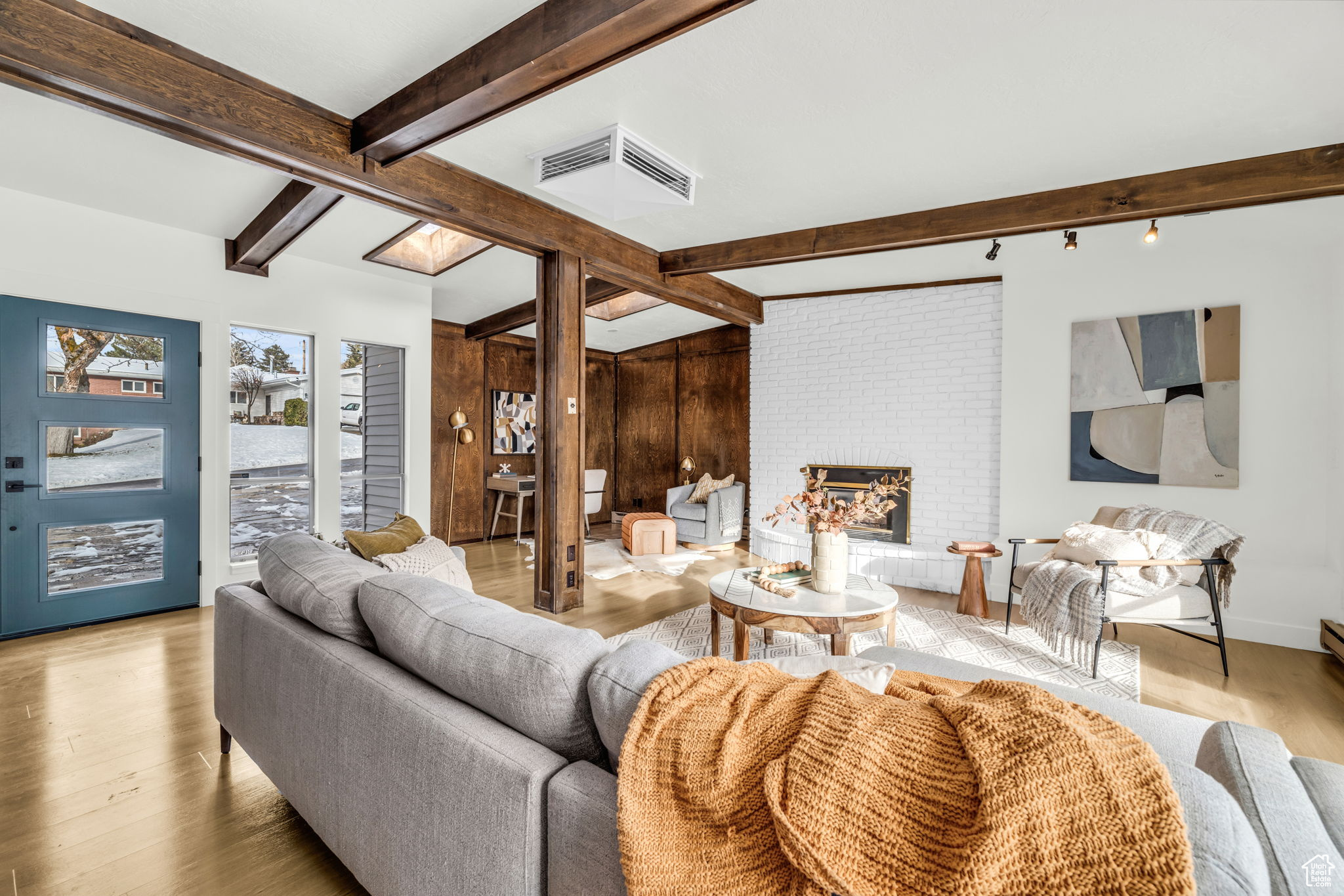 Living room with beam ceiling, a fireplace, and light hardwood / wood-style floors