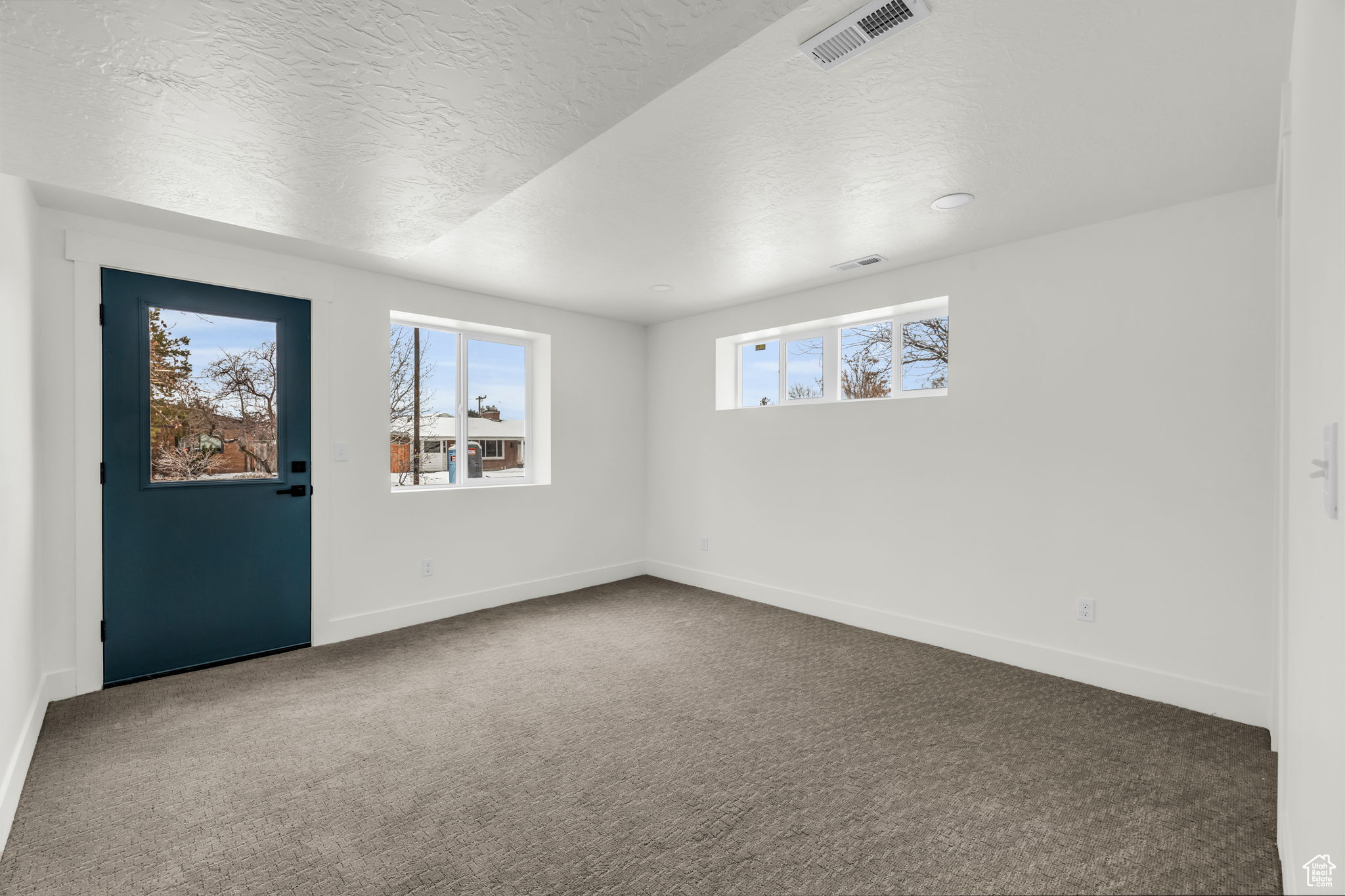 Carpeted spare room featuring a textured ceiling