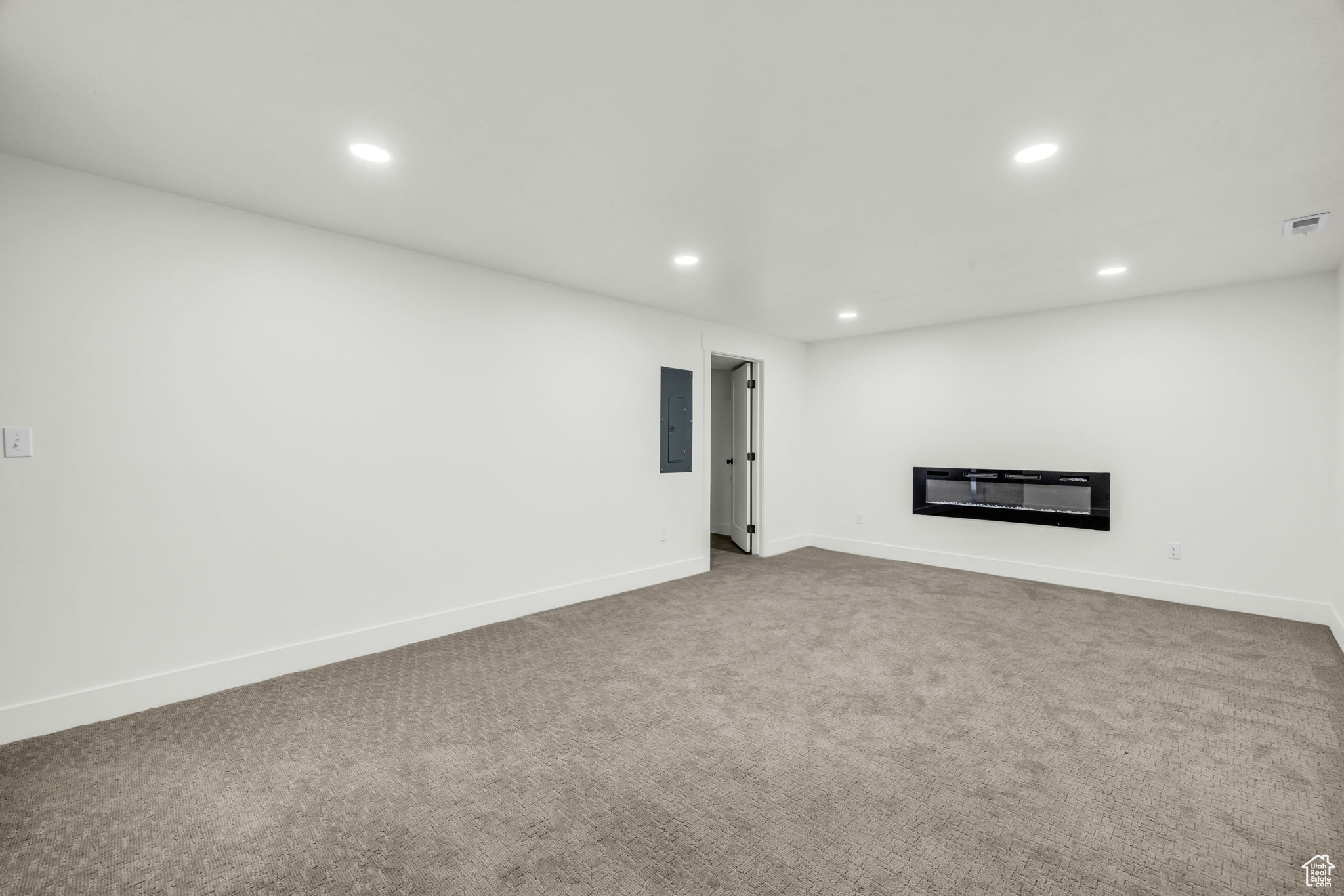 Unfurnished living room featuring carpet and electric panel