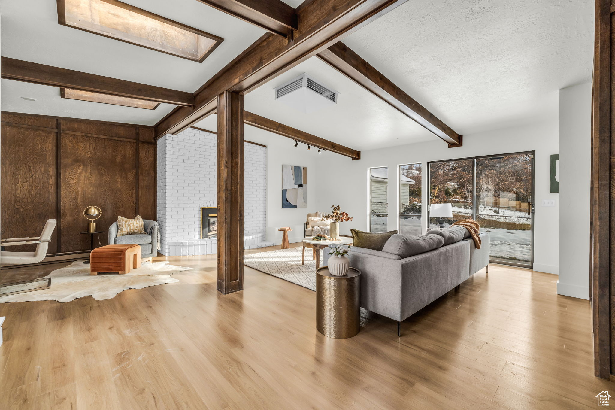 Living room featuring lofted ceiling with beams, a fireplace, light hardwood / wood-style floors, and a textured ceiling