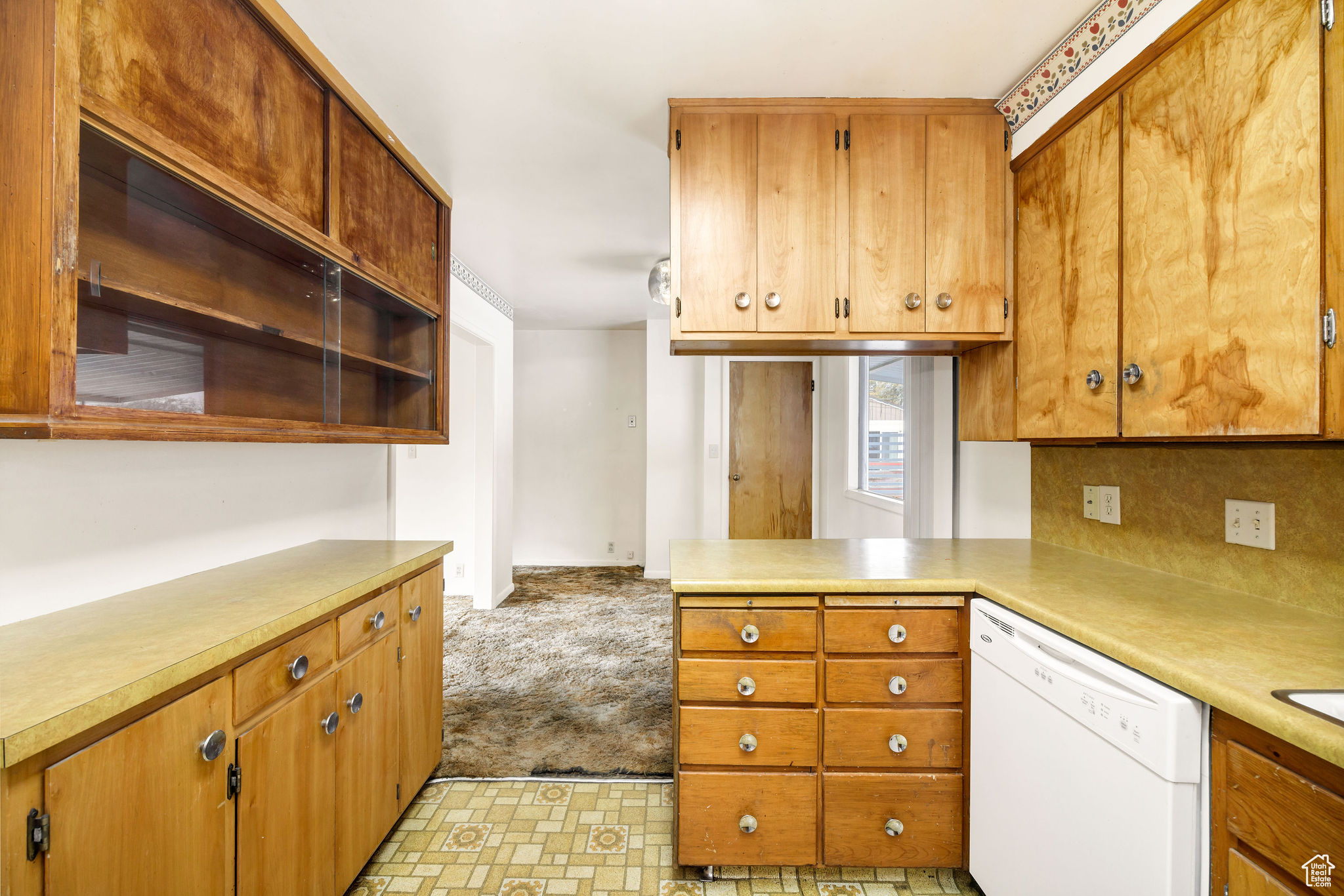 Kitchen with kitchen peninsula, light carpet, and dishwasher