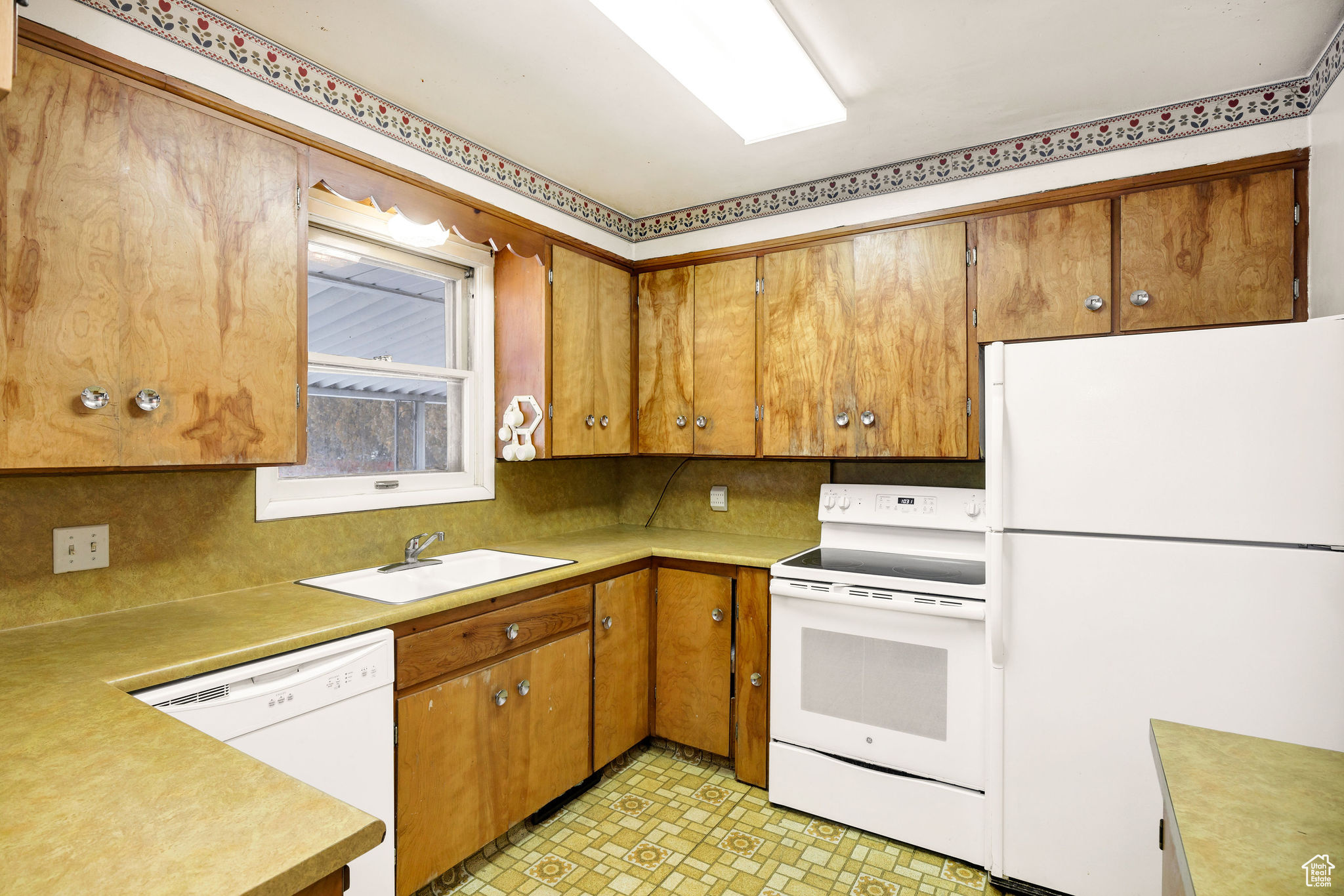 Kitchen with white appliances, backsplash, and sink