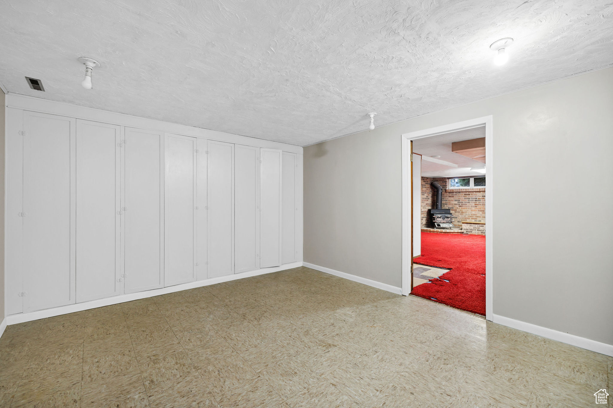 Empty room featuring a wood stove and brick wall