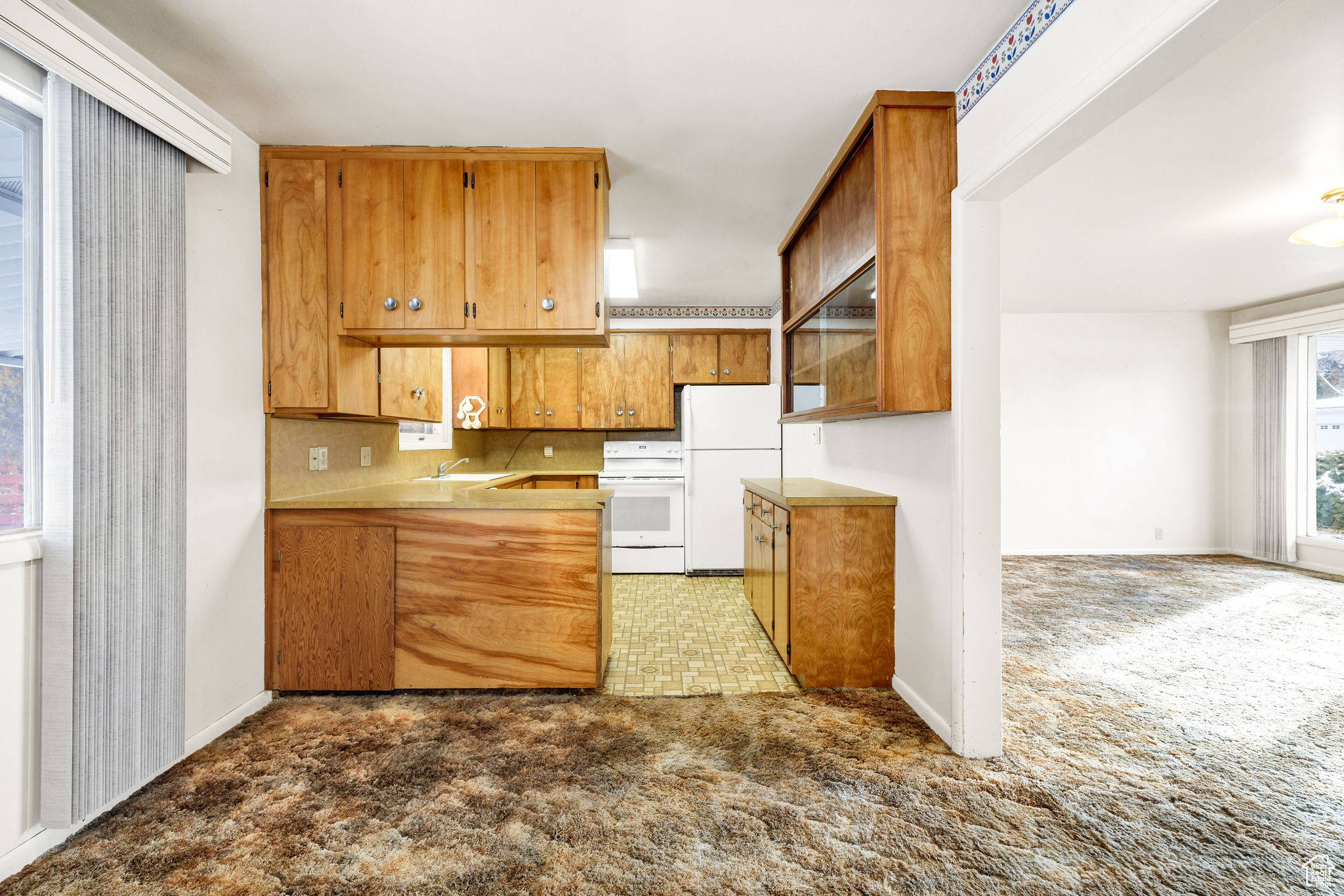 Kitchen featuring light carpet, sink, white refrigerator, and range