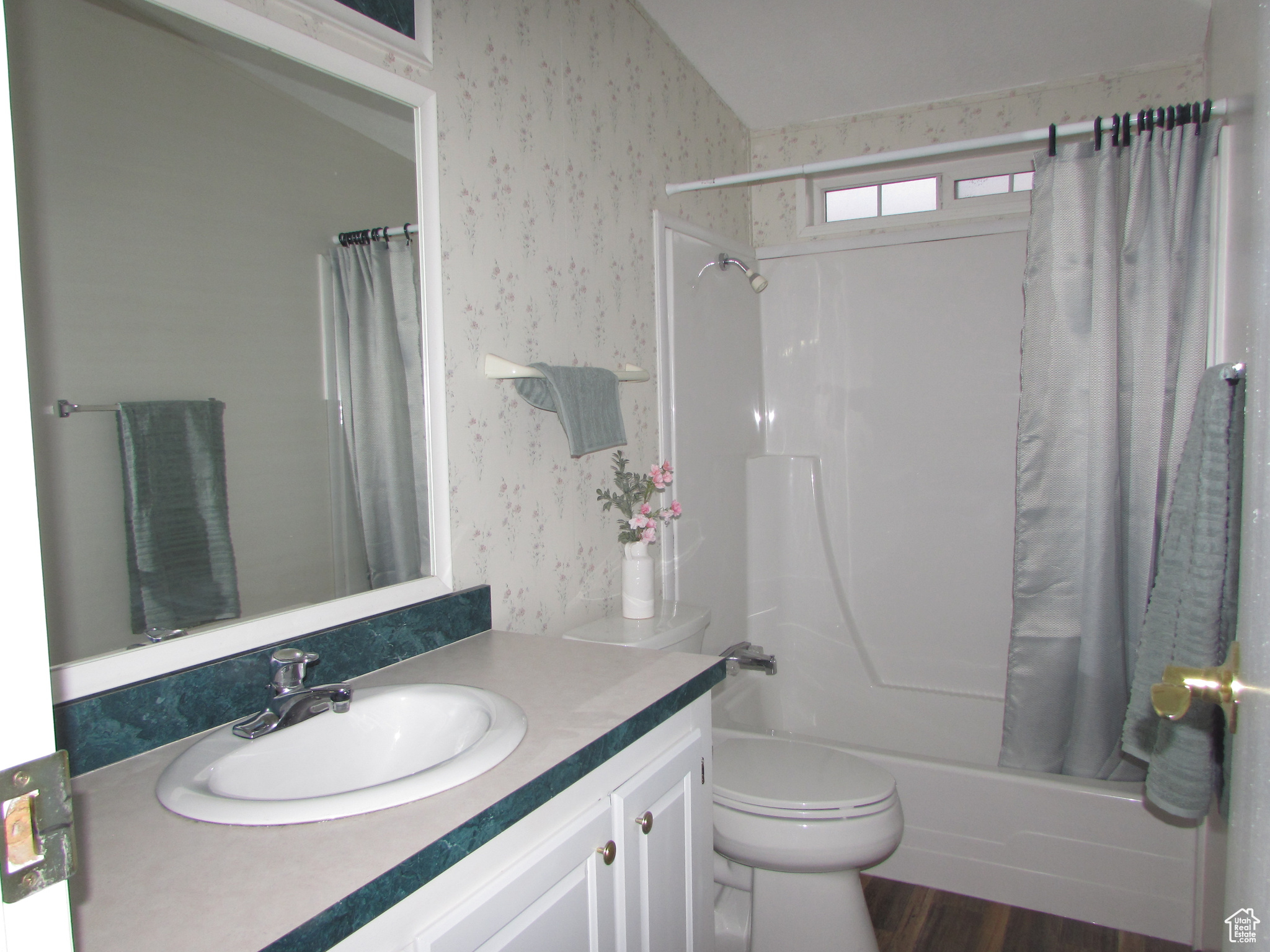 Full bathroom with hardwood / wood-style floors, vanity, toilet, and shower / tub combo