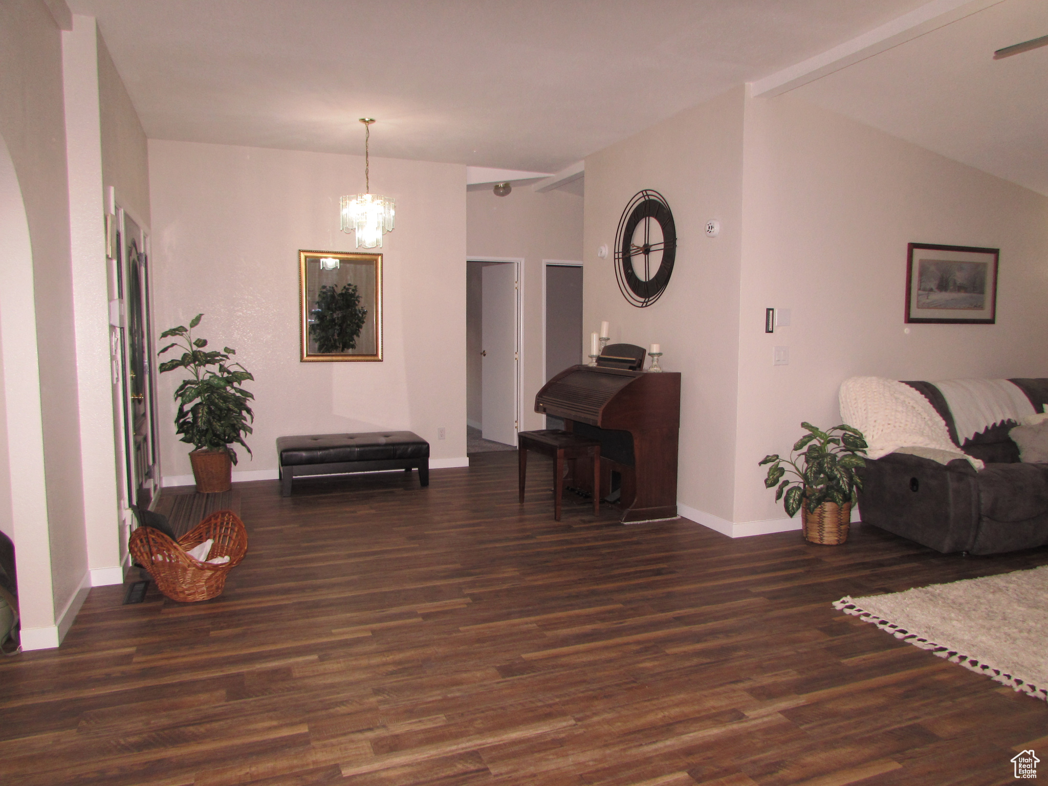 Main entry with lofted ceiling, dark wood-type flooring, and a notable chandelier