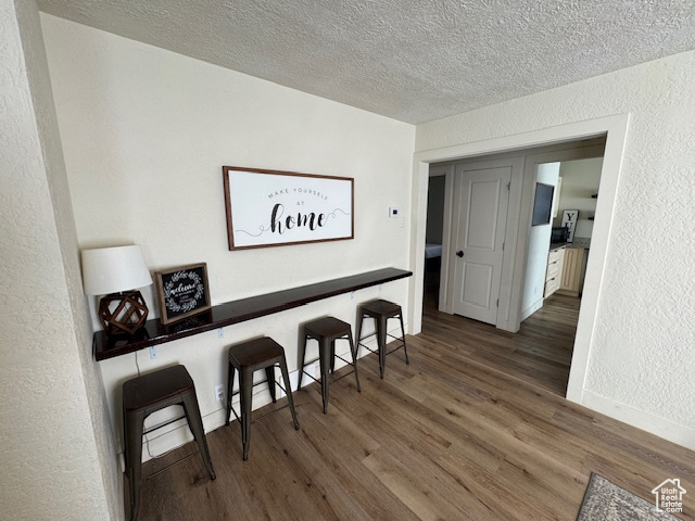 Hall with wood-type flooring and a textured ceiling