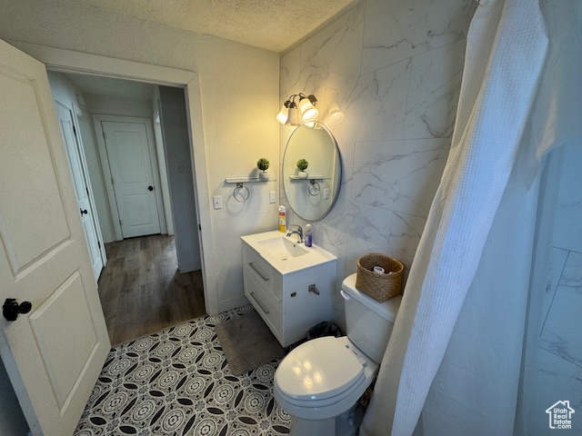 Bathroom with hardwood / wood-style flooring, vanity, a textured ceiling, and toilet