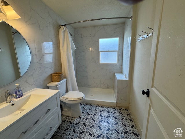 Bathroom with vanity, toilet, curtained shower, and tile walls