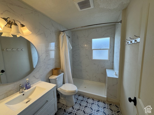 Bathroom featuring vanity, toilet, a textured ceiling, and walk in shower