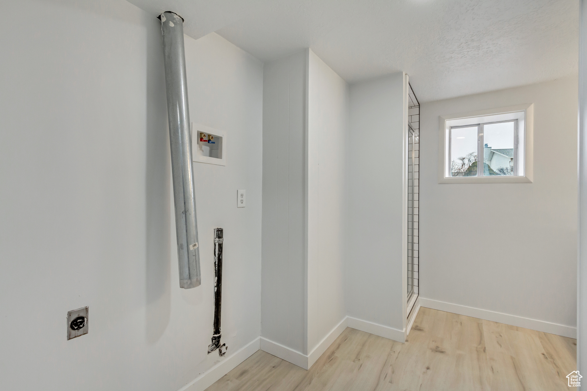 Washroom featuring hookup for an electric dryer, light hardwood / wood-style floors, a textured ceiling, and hookup for a washing machine