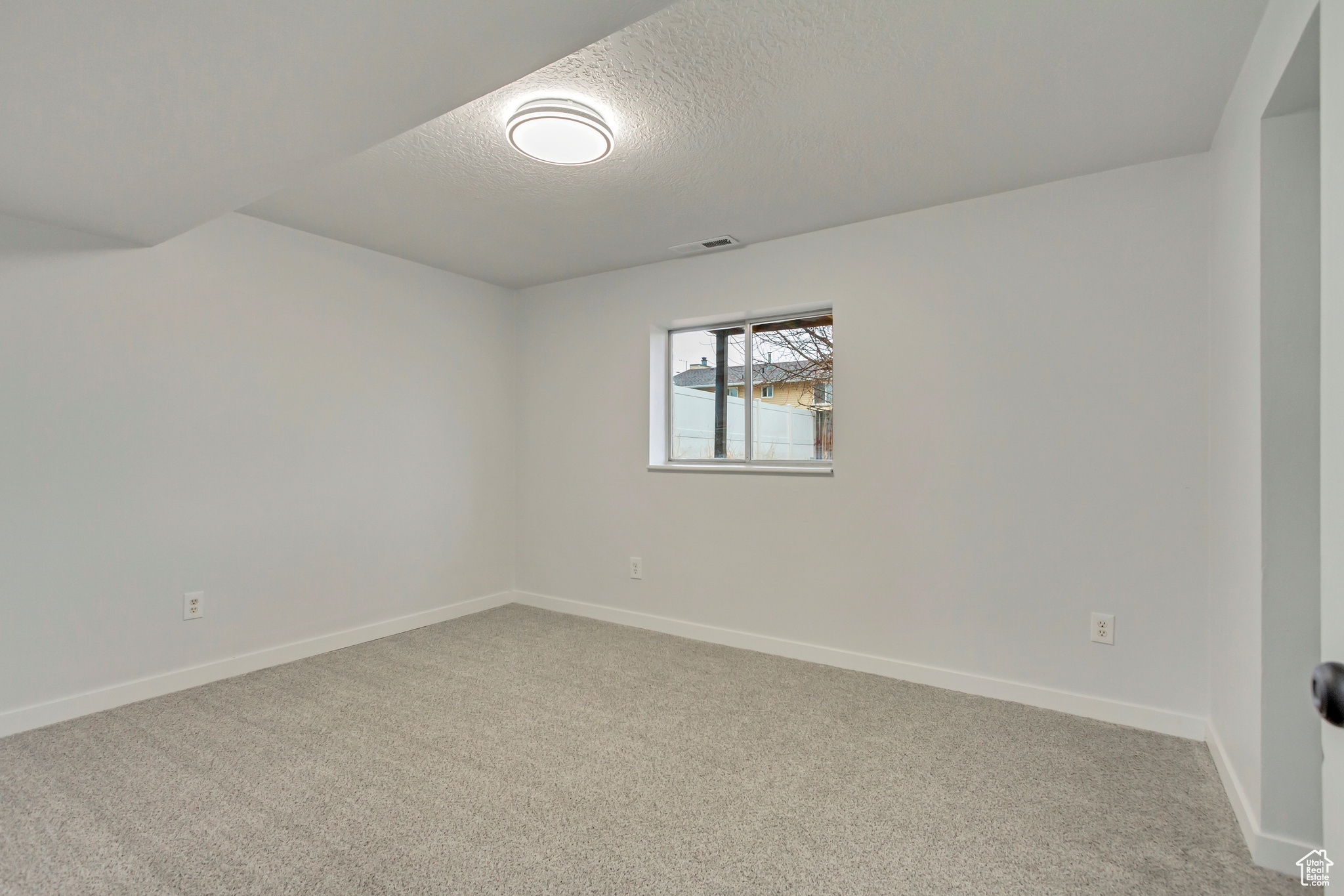 Carpeted spare room with a textured ceiling