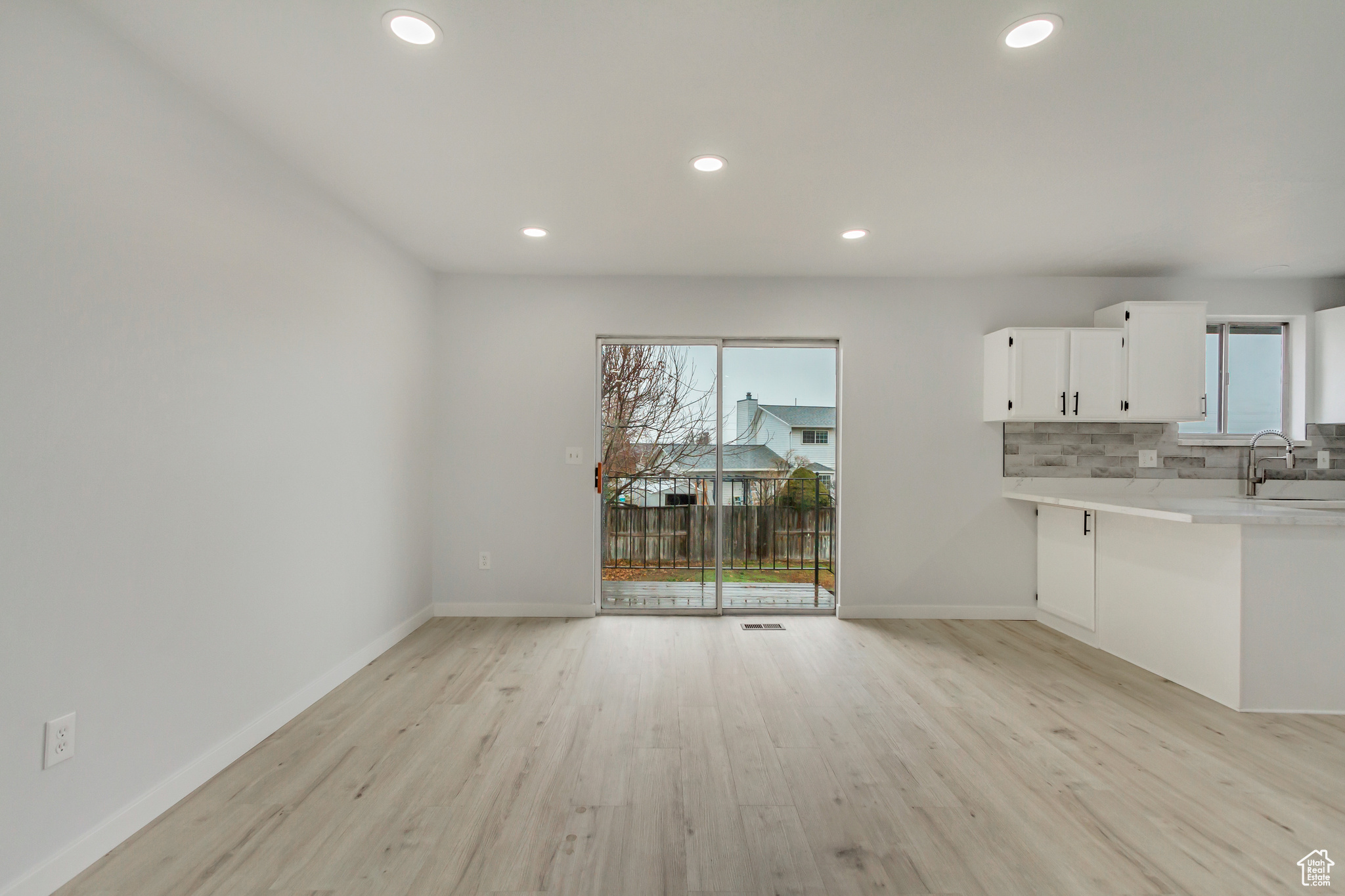 Kitchen with backsplash, white cabinetry, sink, and light hardwood / wood-style floors