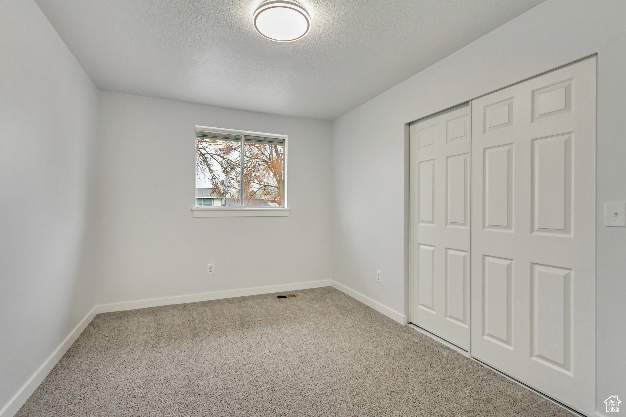 Unfurnished bedroom with carpet, a textured ceiling, and a closet