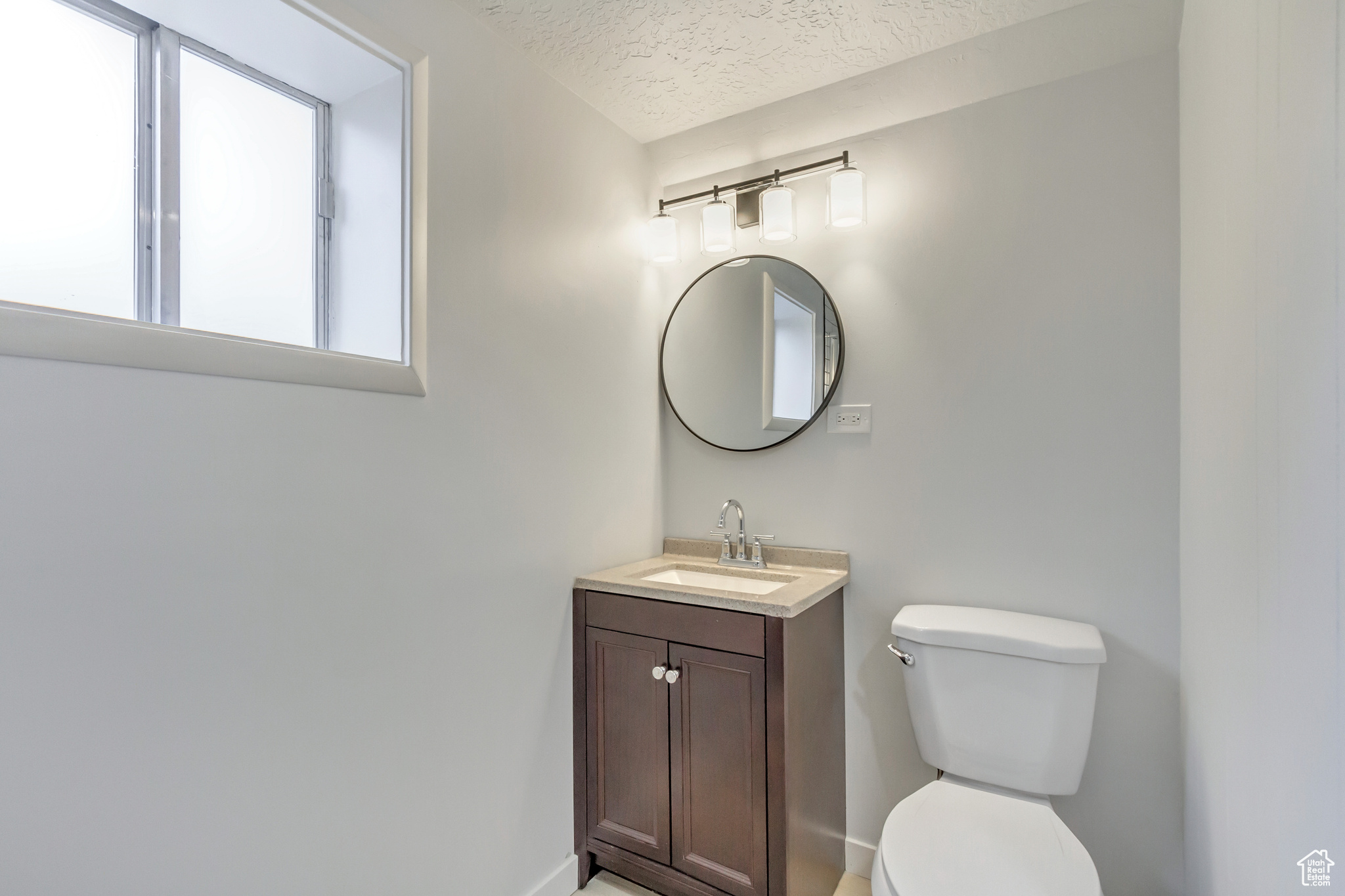 Bathroom featuring vanity, a textured ceiling, and toilet