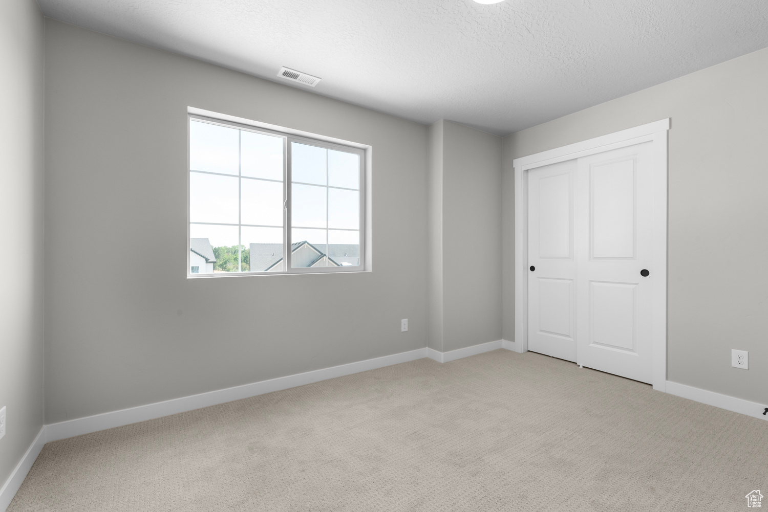 Unfurnished bedroom featuring light colored carpet and a closet