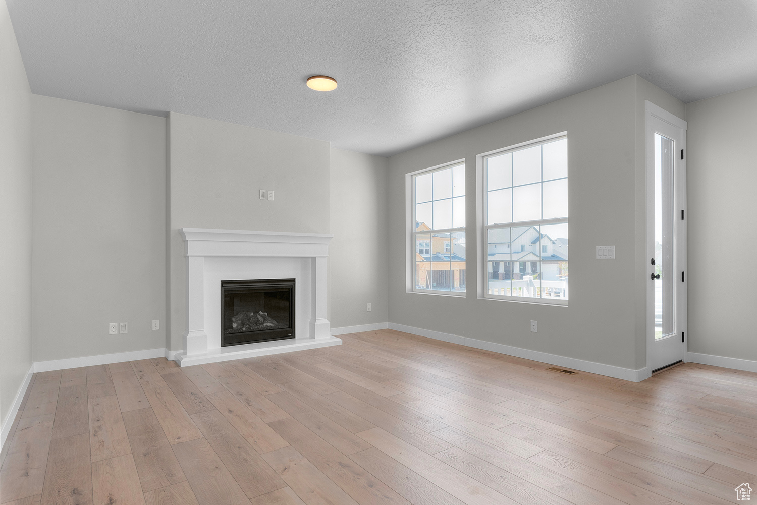 Unfurnished living room with a textured ceiling and light hardwood / wood-style flooring