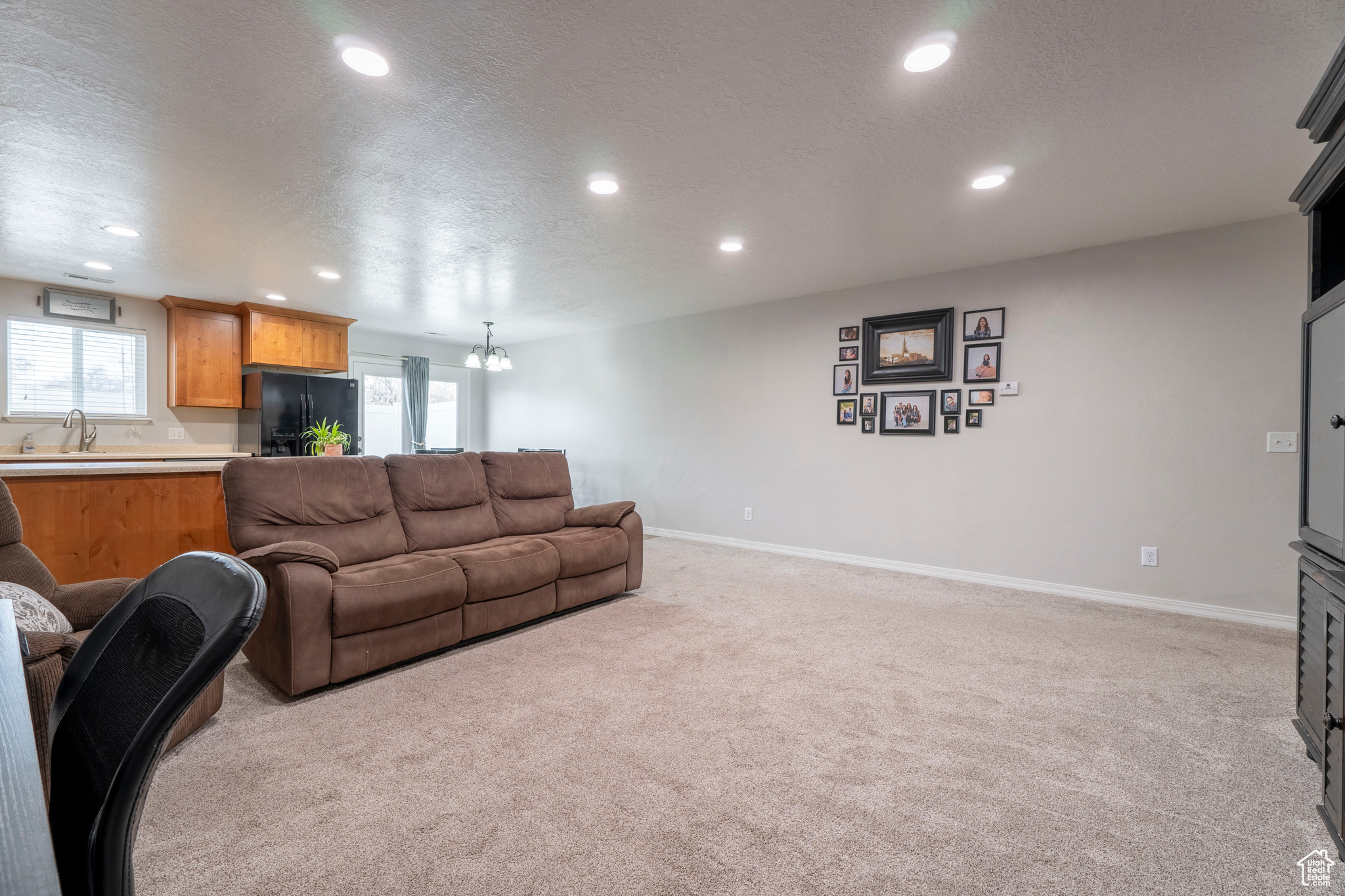 Carpeted living room featuring a chandelier, a textured ceiling, and sink