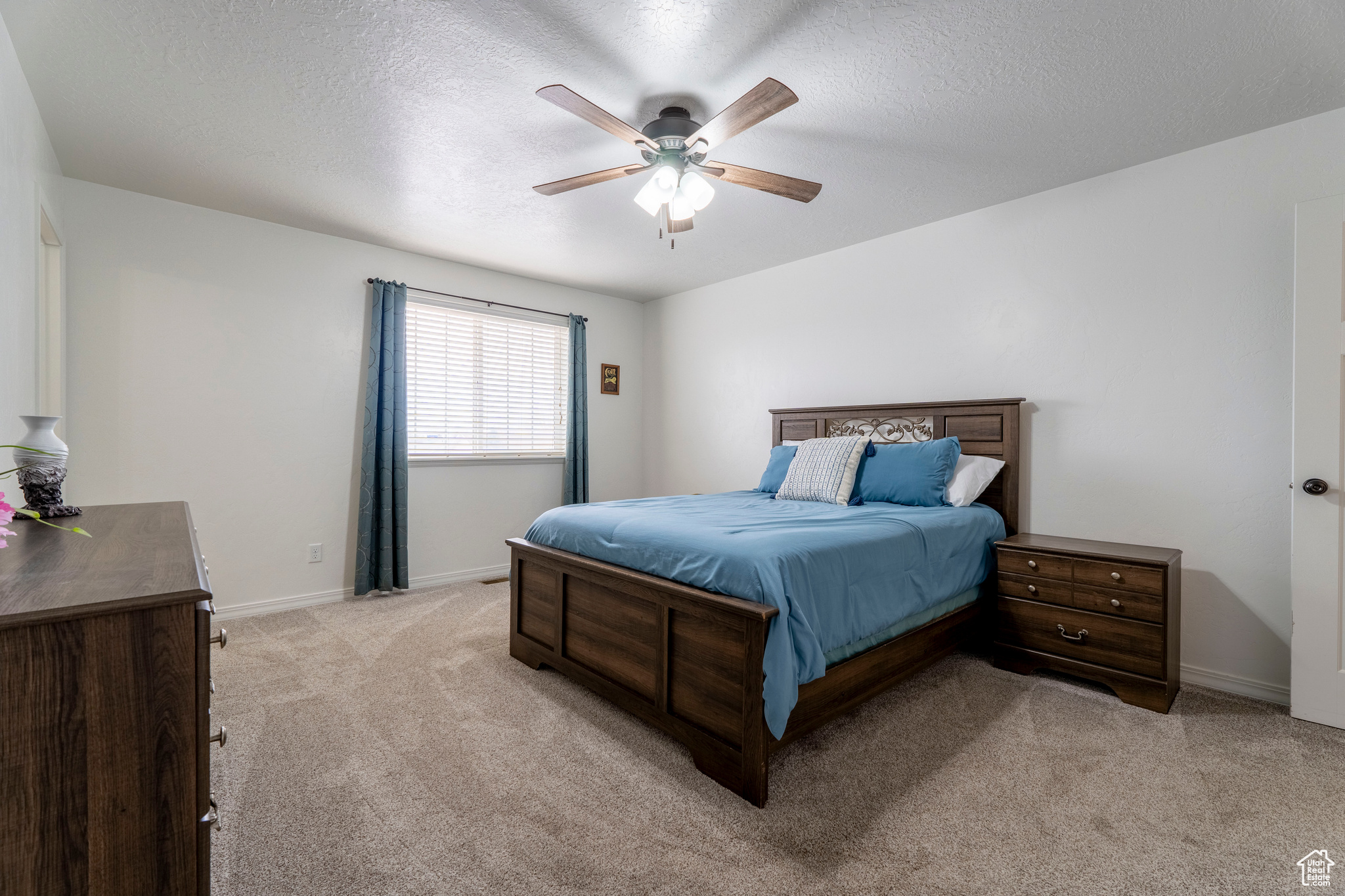 Carpeted bedroom with ceiling fan and a textured ceiling