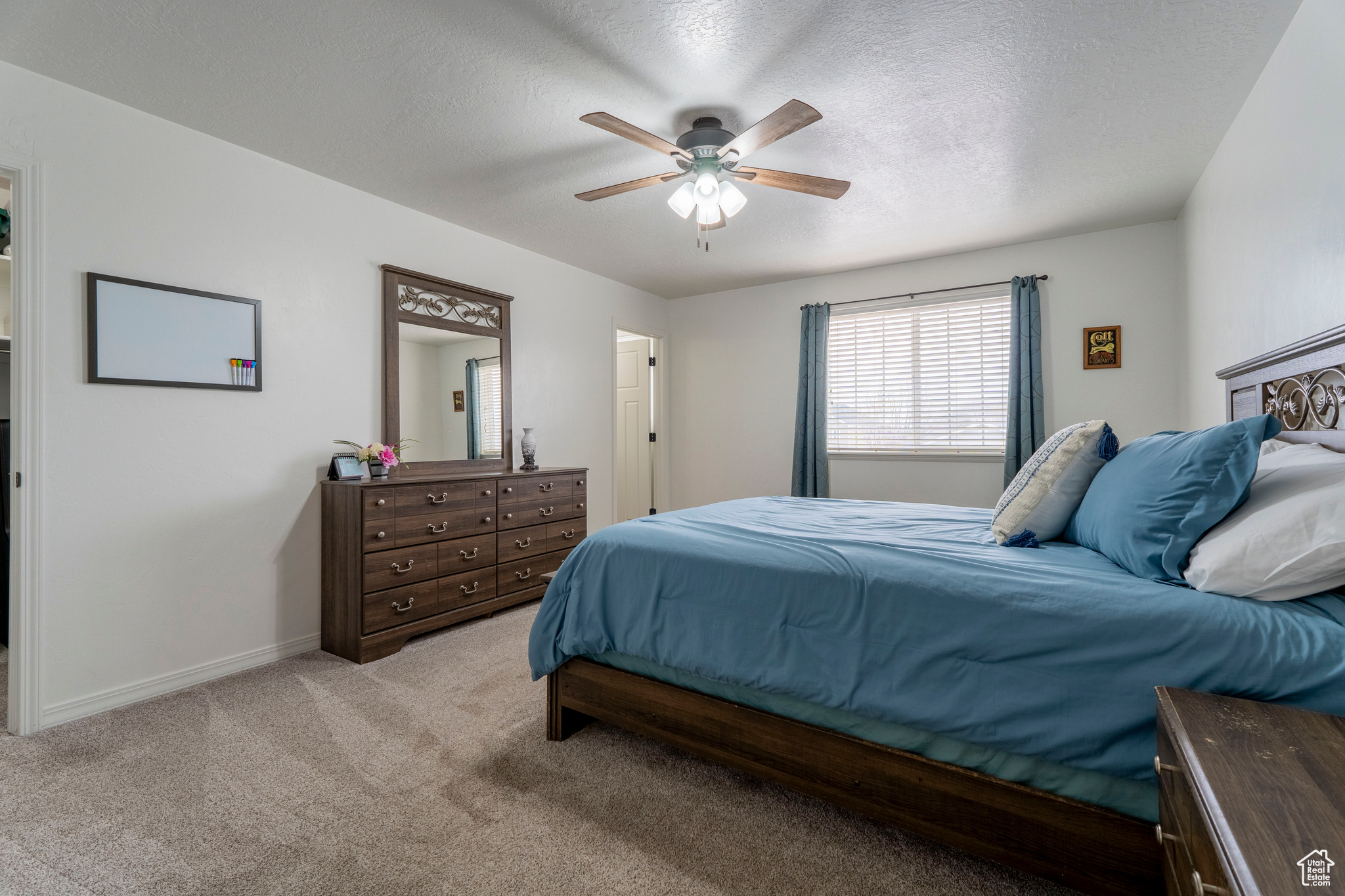 Carpeted bedroom with ceiling fan and a textured ceiling