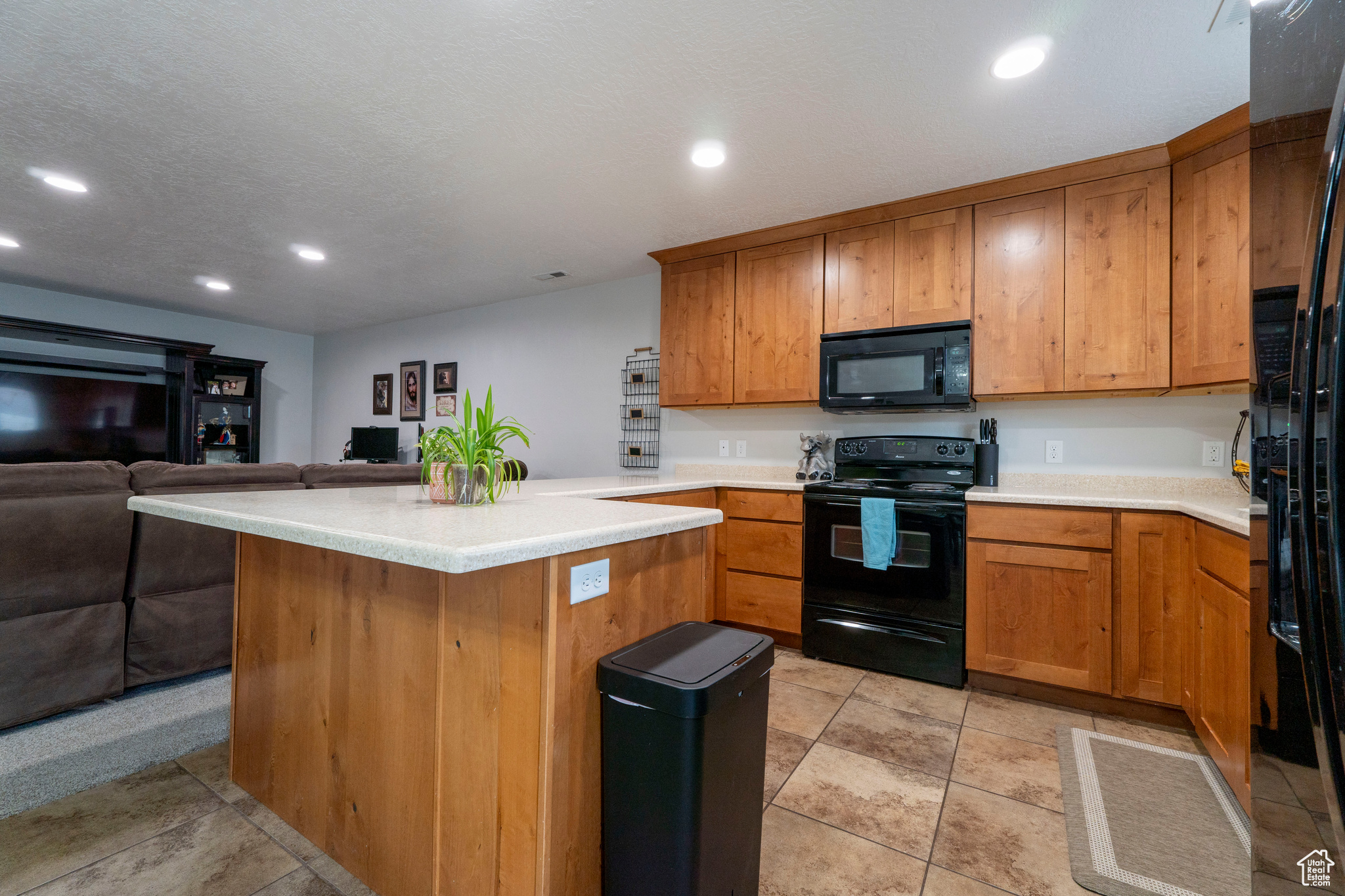 Kitchen featuring kitchen peninsula, a textured ceiling, and black appliances