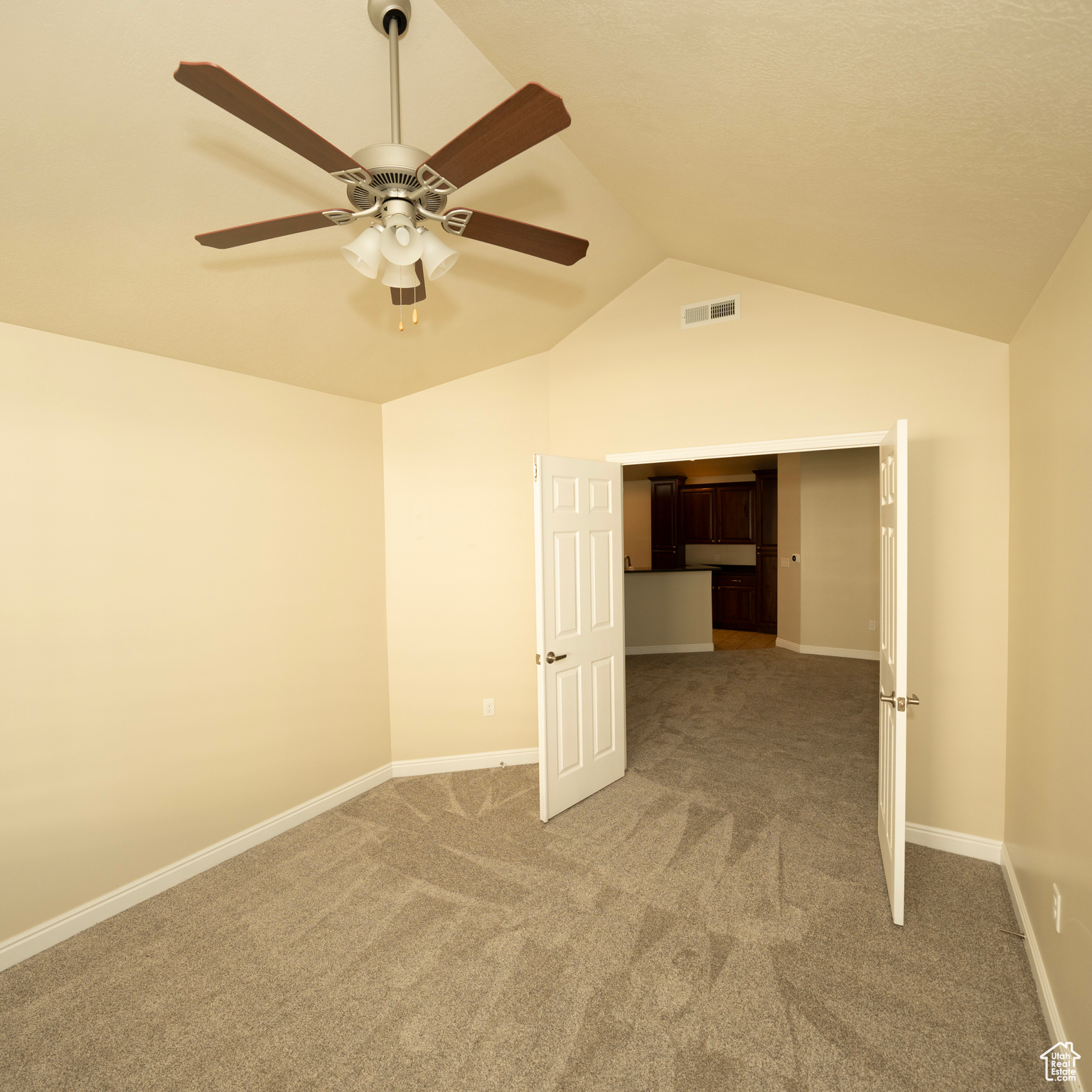 Empty room with carpet flooring, ceiling fan, and lofted ceiling