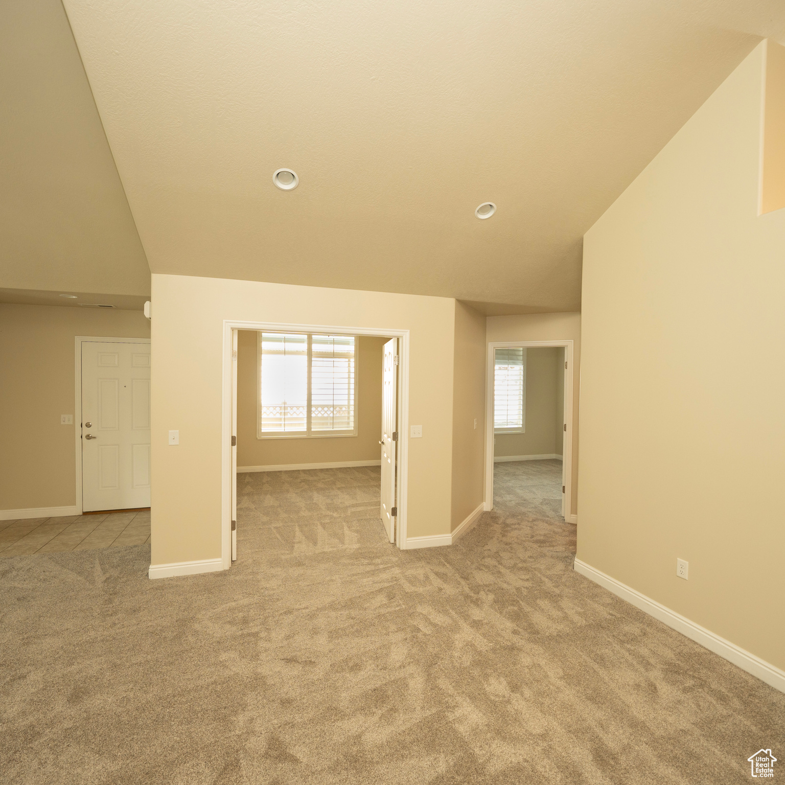 Empty room with light carpet and lofted ceiling