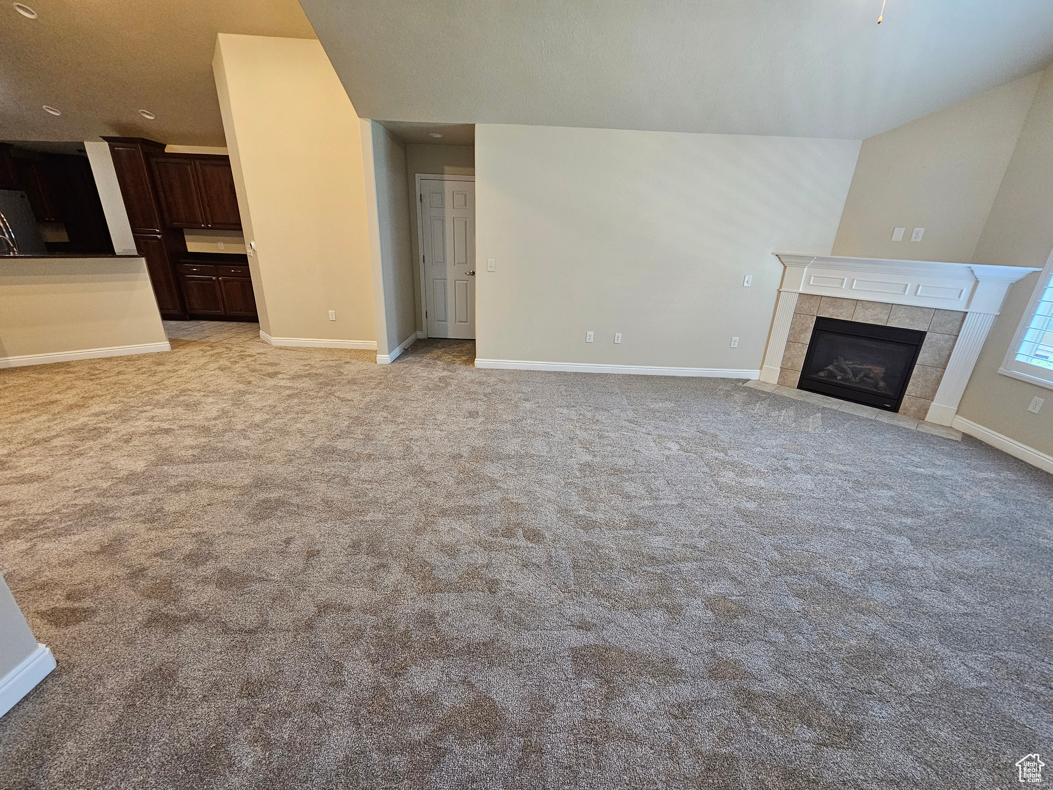 Unfurnished living room with a tile fireplace and light colored carpet