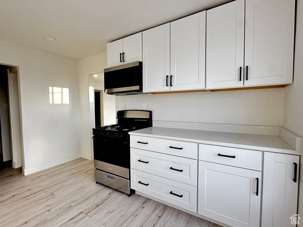 Kitchen with white cabinets, light wood-type flooring, and stainless steel appliances