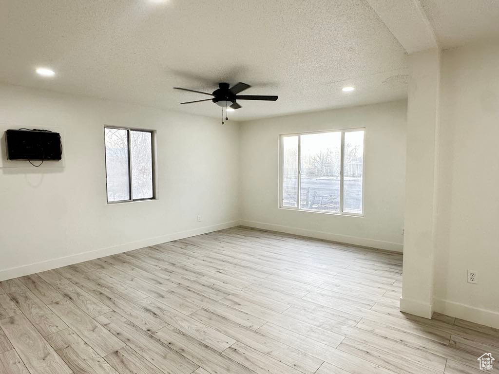 Unfurnished room with ceiling fan, light hardwood / wood-style flooring, and a textured ceiling