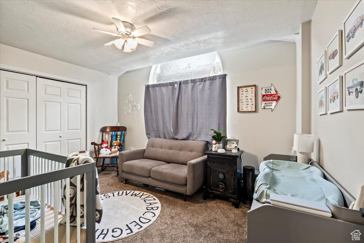 Carpeted bedroom with a ceiling fan and closet