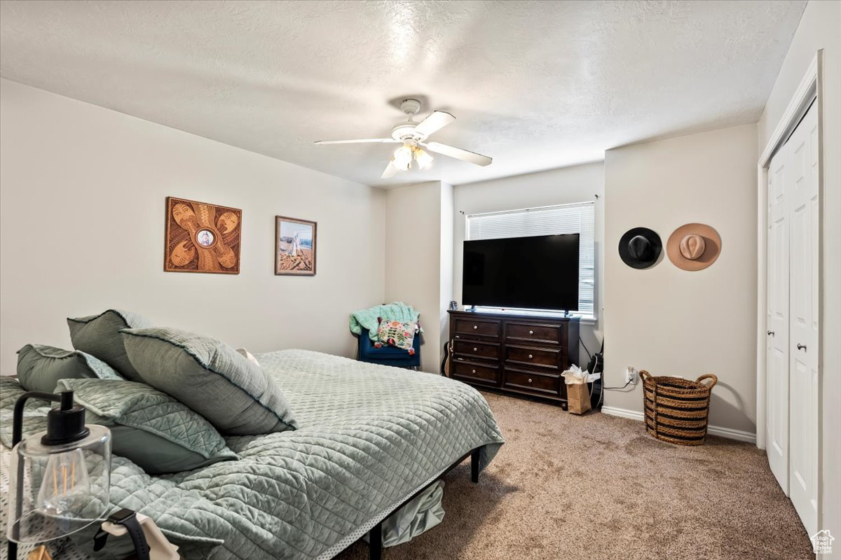 Carpeted bedroom with ceiling fan, and a closet