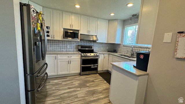 Kitchen with white cabinets, decorative backsplash, stainless steel appliances, and sink