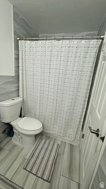 Bathroom featuring a shower with shower curtain and toilet