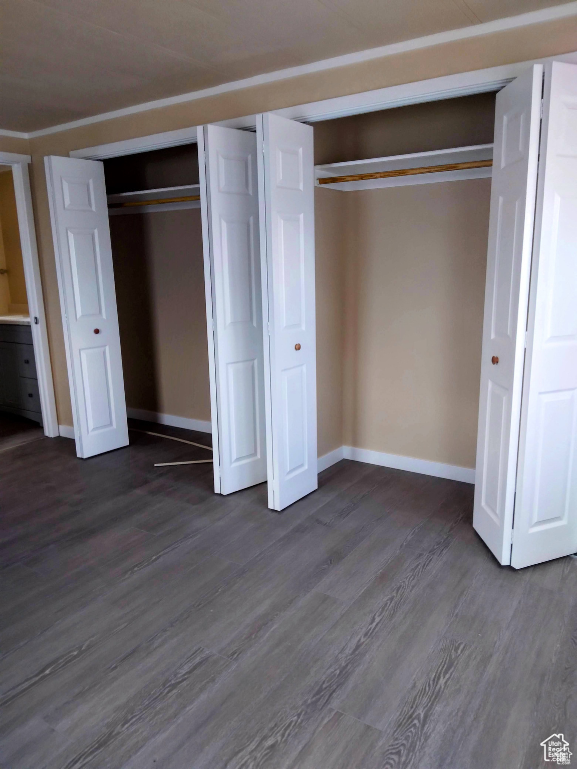 Unfurnished bedroom with ornamental molding, multiple closets, and dark wood-type flooring